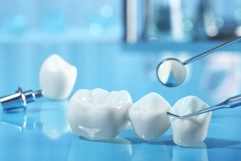 Dental tools examining a three-unit dental crown on a glossy blue surface. The setting is clinical, highlighting dental care and precision.