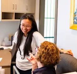 Two people in an office, one seated and one standing, engaged in a friendly conversation.