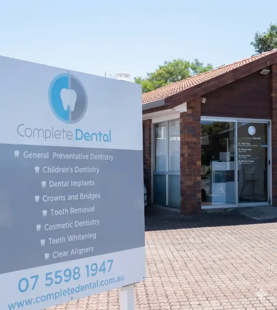 Sign for "Complete Dental" in front of a brick building. Offers services like children's dentistry and implants. Contact info shown.